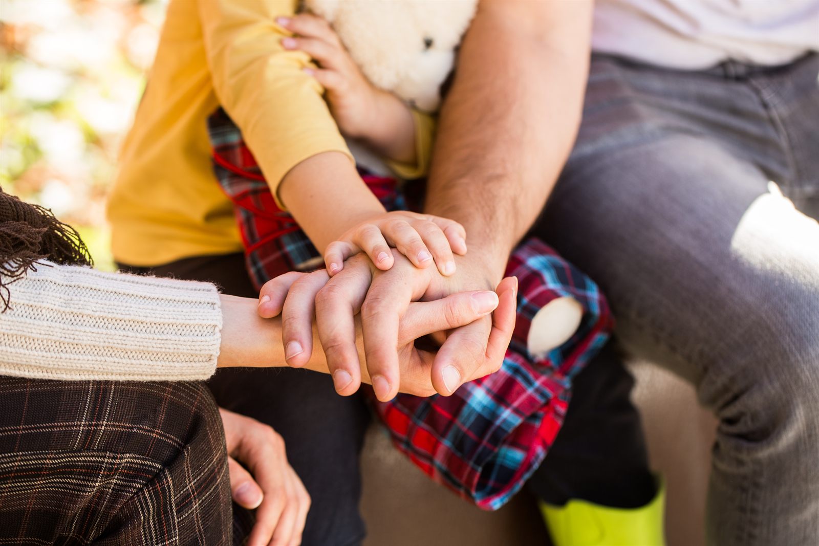 Child and family social work concept: a family stacking their hands together in a show of unity and support